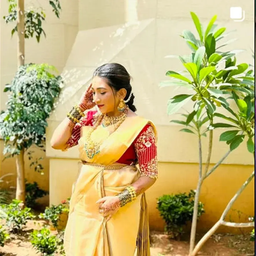 Bride in a gold silk saree with a red embroidered blouse